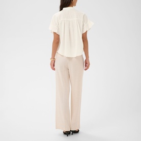 Model wearing Kaffe chalk short-sleeve blouse with flutter sleeves, styled with wide-leg trousers, back view