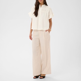 Model wearing Kaffe chalk wide-leg trousers with a white short-sleeve blouse and nude heels.