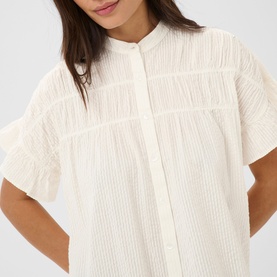 Model wearing Kaffe chalk short-sleeve blouse with textured stripe detail, ruffle trim sleeves, and button-front mandarin collar