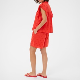 Model wearing Kaffe Poppy Red textured shorts and matching sleeveless blouse, styled with red flat sandals
