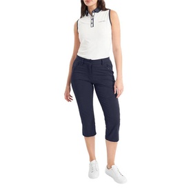 Model wearing Calvin Klein Golf navy cropped trousers with white sleeveless polo shirt and white trainers.