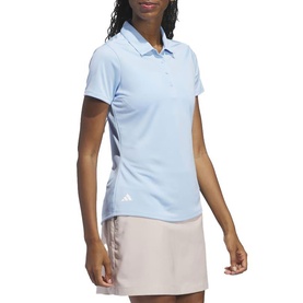 Model wearing Adidas Golf women's polo shirt in Clear Sky blue, styled with a light pink skort. Short sleeves with logo detail.