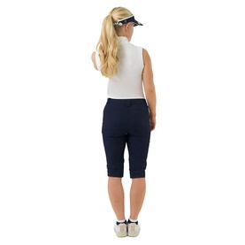 Model wearing Pure Golf navy cropped shorts with cuffed hem, styled with white sleeveless top, visor and white trainers, rear view