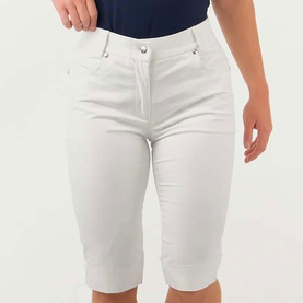 Model wearing Pure Golf white knee-length shorts with silver button detailing, styled with a navy top.