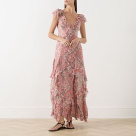 Model wearing Rixo Butterfly Paisley Orange silk maxi dress with ruffle tiers, V-neckline, and cap sleeves, styled with black strappy sandals