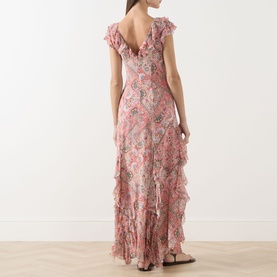Model wearing Rixo silk maxi dress in Butterfly Paisley Orange with ruffle hem, V-back neckline and cap sleeves, styled with flat sandals