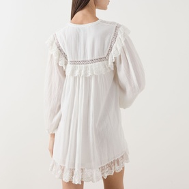 Model wearing Rixo Lilly Embroidery Ivory dress, back view, showing lace trim detailing, ruffled hem, and voluminous long sleeves.