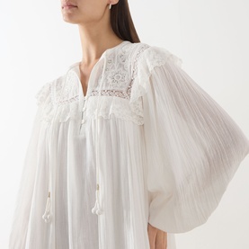 Model wearing Rixo Lilly Embroidery Ivory dress with lace yoke detail, billowing sleeves and tassel tie neckline.