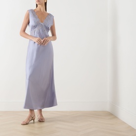 Model wearing Rixo dusty blue sleeveless midi dress with V-neck and floral embroidery detail, styled with beige heeled mules.