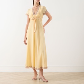 Model wearing Rixo Butter Yellow silk midi dress with cap sleeves, lace trim hem, and tie-front detail, styled with strappy heeled sandals.