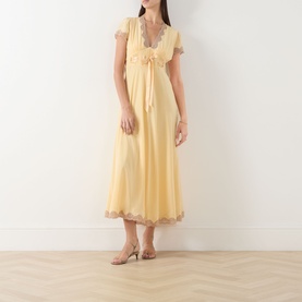 Model wearing Rixo butter yellow silk midi dress with lace trim, flutter sleeves and tie-front detail, styled with strappy heeled sandals