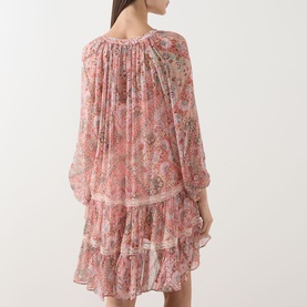 Model wearing Rixo dress in Cara Bandana Orange, sheer tiered mini with long sleeves, ruffle hem and paisley floral print, back view.