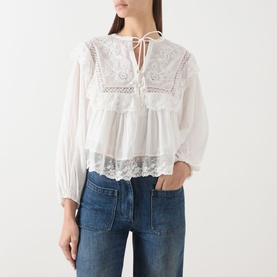 Model wearing Rixo ivory cotton blouse with lace embroidery panels, tie neck, balloon sleeves and lace hem trim, styled with blue jeans