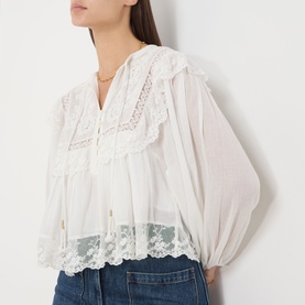 Model wearing Rixo ivory cotton blouse in Lilly Embroidery, featuring lace trim, oversized collar and balloon sleeves, styled with blue denim jeans.