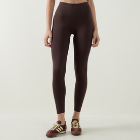 Model wearing Varley Coffee Bean high-waist leggings, styled with brown and yellow Adidas trainers