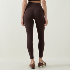 Model wearing Varley leggings in Coffee Bean, high-waisted with a smooth finish, styled with brown trainers.