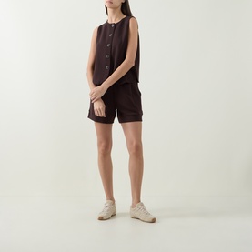 Model wearing Varley Coffee Bean shorts styled with matching sleeveless button-front top and cream trainers.