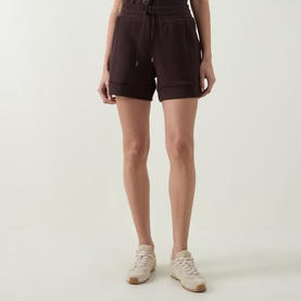 Model wearing Varley Coffee Bean shorts in viscose blend, styled with cream trainers