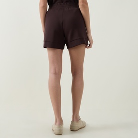 Model wearing Varley Coffee Bean shorts, rear view, with cream trainers. Relaxed fit with cuffed hem and elasticated waistband.