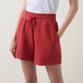 Model wearing red drawstring waist shorts with side pockets and cuffed hem, styled with a white top