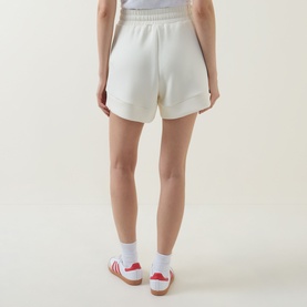 Model wearing Varley Pristine shorts, back view, styled with white socks and red stripe trainers