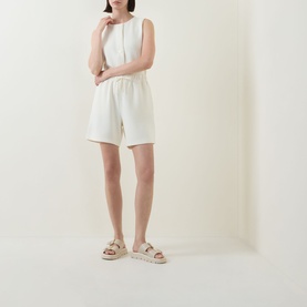 Model wearing Varley Pristine shorts with matching sleeveless top and beige chunky slide sandals.