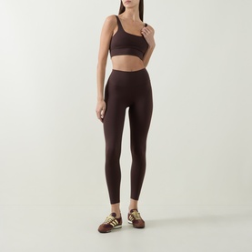 Model wearing Varley Coffee Bean Sports Bra with matching high-waist leggings and green stripe trainers.