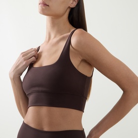 Model wearing Varley Sports Bra in Coffee Bean, featuring thin straps and a square neckline, styled with matching high-waist leggings.