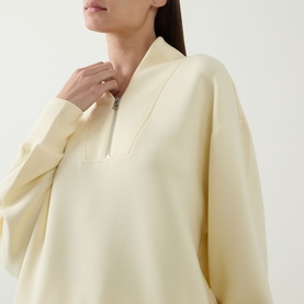 Model wearing Varley Anise Flower sweat top with half-zip neckline and relaxed fit, styled with a silver ring.
