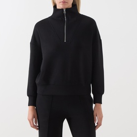Model wearing Varley black half-zip sweatshirt with funnel neck, styled with black trousers.