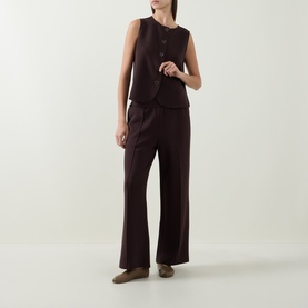 Model wearing Varley Coffee Bean trousers, styled with matching sleeveless vest and khaki flat shoes