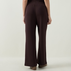Model wearing Varley Coffee Bean wide-leg trousers, rear view, elasticated waistband, relaxed flared leg silhouette.