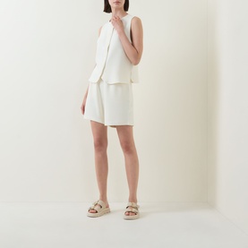 Model wearing Varley Pristine sleeveless top with matching white shorts and beige flatform sandals.