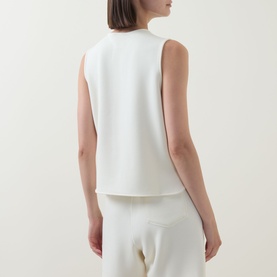 Model wearing Varley sleeveless top in Pristine, back view, styled with matching wide-leg trousers in cream.