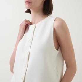 Model wearing Varley top in Pristine, sleeveless with crew neckline and front button fastening, close-up detail view