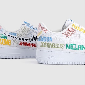 Nike Air Force 1 trainers in white with multicolour city name graphics including London, Milan, Shanghai and Los Angeles printed across upper