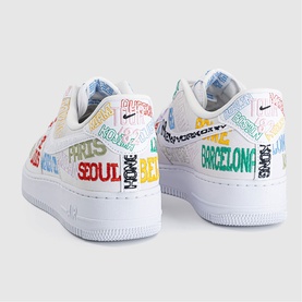 Nike white low-top trainers with multicoloured city name print including Paris, Seoul, Barcelona, white rubber sole, black Swoosh logo