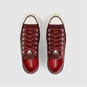 Converse Chuck Taylor low-top trainers in Smoked Paprika, red leather upper, cream foxing stripe, white laces, overhead flat-lay view.