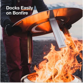 Solo Stove Bonfire Heat Deflector being docked onto a lit Bonfire fire pit, with visible flames below, demonstrating easy installation