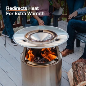 Solo Stove Bonfire Heat Deflector in stainless steel, fitted atop a fire pit on a deck, redirecting heat outward with flames visible below
