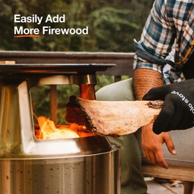 Solo Stove Cast Iron Bonfire Grill Top and Hub in use, person adding firewood to lit fire pit outdoors with text overlay