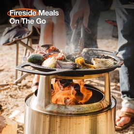 Solo Stove Cast Iron Bonfire Grill Top and Hub in use over open flame, grilling vegetables and meat outdoors at a campsite.
