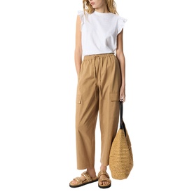 Model wearing Whistles white ruffle-sleeve top with tan cargo trousers, styled with brown sandals and a woven straw tote bag.