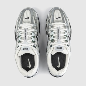 Nike trainers in white and off-white, overhead view showing mesh and synthetic upper, black branding, white rubber sole with swoosh detail