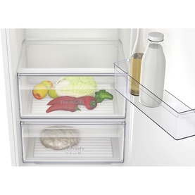 Neff integrated fridge interior showing two clear salad drawers and a door bottle rack with fresh produce and a milk bottle visible