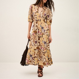 Model wearing Bash yellow ikat-print midi dress with puff sleeves, styled with black fringed bag and strappy sandals