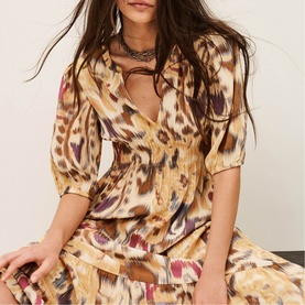 Model wearing Bash yellow ikat-print wrap dress with elasticated waist and three-quarter sleeves, styled with a silver layered necklace