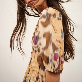 Model wearing Bash yellow abstract ikat-print dress with puff sleeves and pleated fabric detail