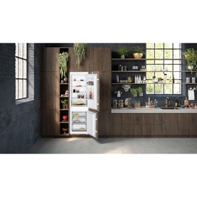 Neff built-in fridge freezer in white, integrated into dark wood kitchen cabinetry, shown open with food items inside