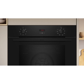 Neff black built-in single electric oven with rotary dials and red digital display, shown integrated in a fitted kitchen unit